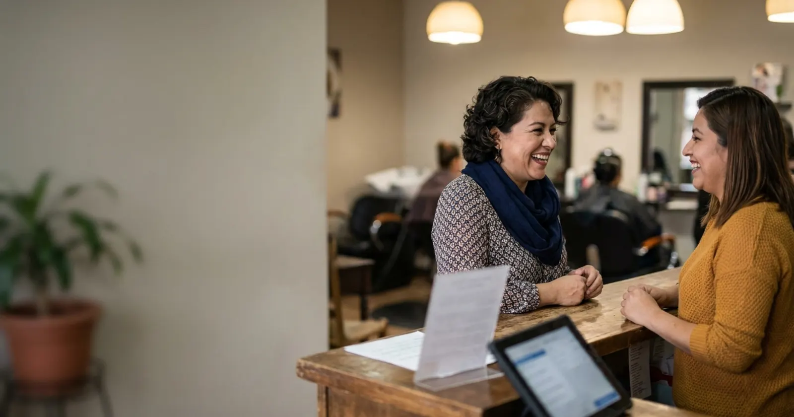 Clienta platica con la recepcionista de un salón de belleza